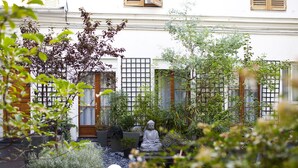 A serene garden with a Buddha statue, a white spherical object, and a variety of plants. - CamParis - B&B - Chambre d'hôtes (Paris)