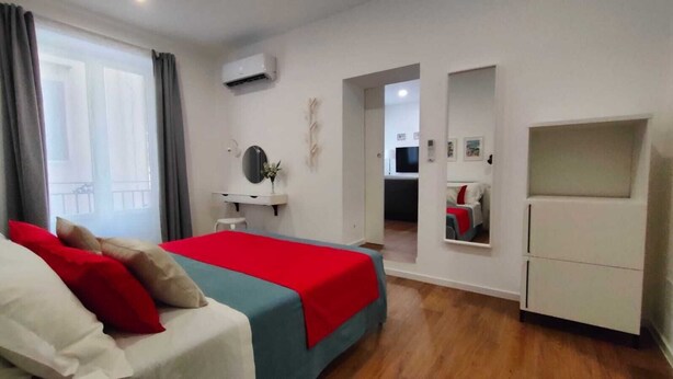 Een slaapkamer met een bed, een kledingkast, een spiegel en een raam.