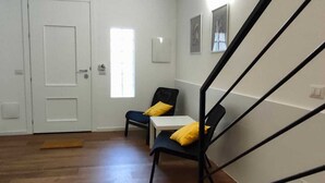 Een ruime kamer met een houten vloer, een zwarte trap en een witte deur.