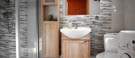 A modern bathroom with a wooden vanity, a sink, a toilet, and a washing machine.