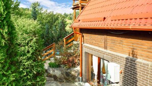 Un edificio in legno con tetto rosso, parete in mattoni e una scala in legno che conduce a un balcone.