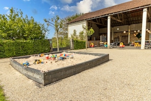 A sandy play area with toy vehicles and a building with a tiled roof and columns. - Maison Périgourdine de Caractère, 2-8 Personnes, Piscine, Située au Calme (Jayac)