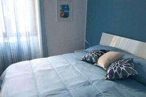Une chambre à coucher avec un lit, des oreillers et une fenêtre avec des rideaux.