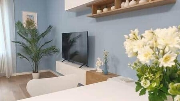 Ein Wohnzimmer mit Flachbildfernseher, Topfpflanze und Blumenvase.