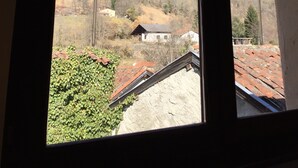 Une vue par la fenêtre sur un paysage montagneux, avec une maison et une colline.