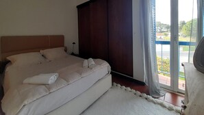 Un dormitorio con una cama grande, cabecera de madera, mesita de noche y vistas al exterior a través de una puerta corrediza de vidrio.