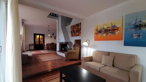 Una sala de estar con un sofá, una mesa de centro, una chimenea y obras de arte en las paredes.