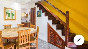Ein Essbereich mit Holztisch und -stühlen, eine Treppe mit Holzbalkonen und Kunstwerke an den Wänden.