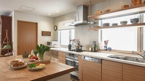 A modern kitchen with wooden cabinets, a stainless steel sink, and a window providing natural light. - Chalet Murasaki (Kutchan)