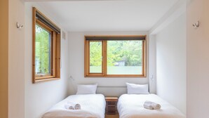 A small, bright room with two beds, a window, and a radiator. - Chalet Murasaki (Kutchan)