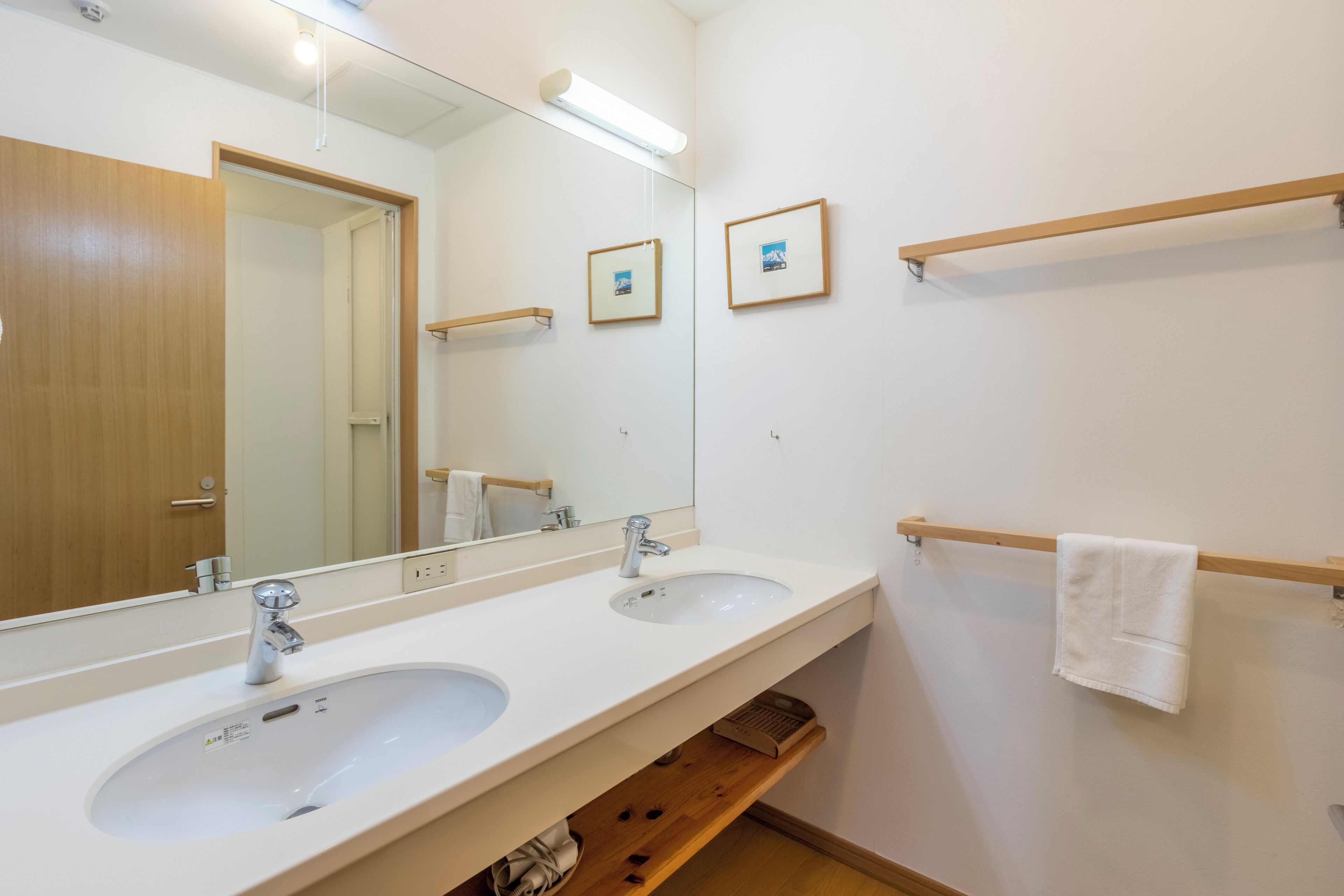 A bathroom with two sinks, a mirror, and a towel rack.