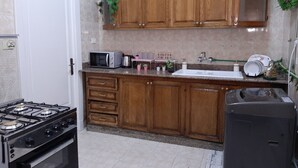 A kitchen with wooden cabinets, a microwave, a sink, and a stove. - Royal Apartment in Talaat Harb Downtown  (Cairo)