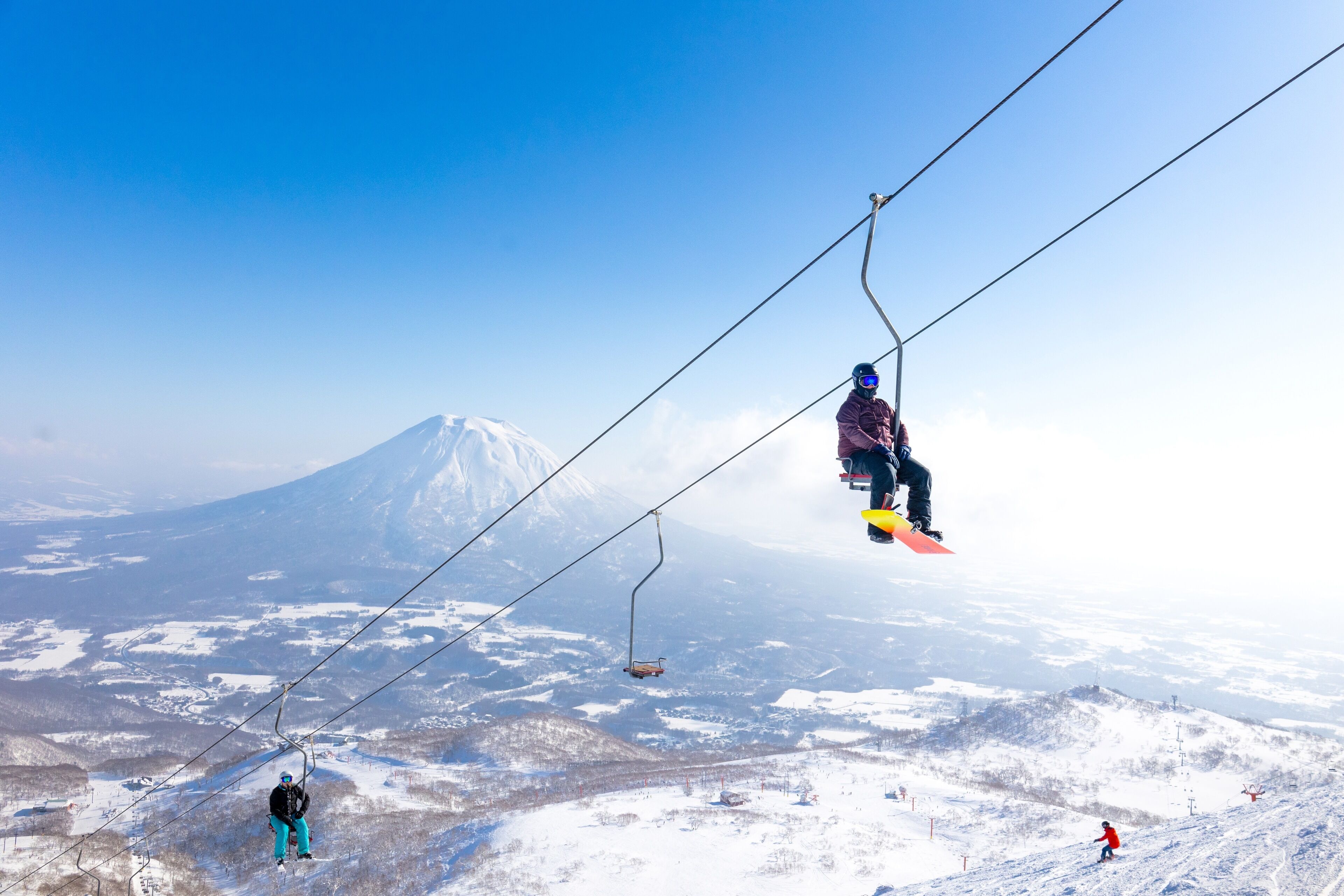 Eine Seilbahn vor einer verschneiten Berglandschaft.