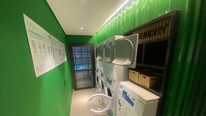 Uma lavanderia com paredes verdes, várias máquinas de lavar e uma secadora.