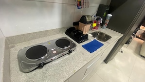 Uma bancada de cozinha com uma cafeteira, um bule e um guardanapo azul.