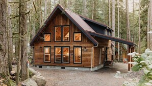 A wooden cabin with a gabled roof, multiple windows, and a covered porch area. - 39gs - Hot Tub - Wi-fi - Pets Ok 3 Bedroom Cabin by RedAwning (Deming)