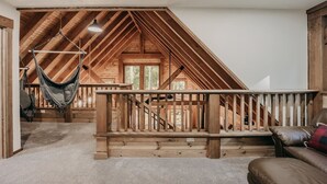 A loft bedroom with a wooden ceiling, a hammock, a wooden bench, and a leather couch. - 39gs - Hot Tub - Wi-fi - Pets Ok 3 Bedroom Cabin by RedAwning (Deming)