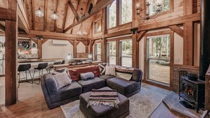 A spacious living room with a large sectional sofa, a fireplace, and a kitchen area visible through an open door. - 39gs - Hot Tub - Wi-fi - Pets Ok 3 Bedroom Cabin by RedAwning (Deming)