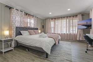 A bedroom with a bed, bedside table, lamp, and a TV on the wall. - Charming Retreat In The Heart Of Des Plaines 3 Bedroom Residence by RedAwning (Des Plaines)