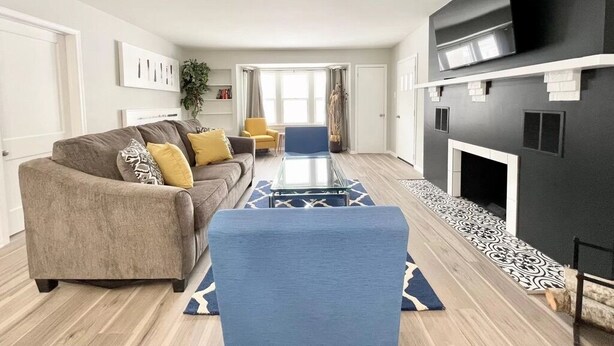 A modern living room with a sofa, armchairs, a coffee table, and a fireplace. - Muskegon Cozy Cutler Cottage. (Muskegon)