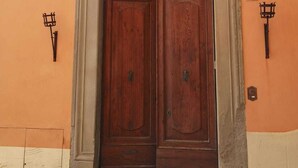 Una puerta doble de madera con marco de piedra, integrada en un edificio con pared naranja.