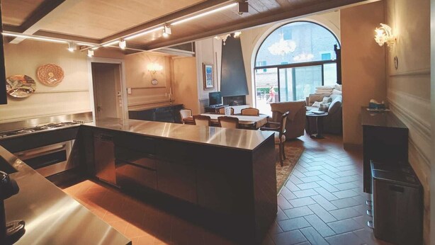 Una cocina moderna con una isla central, una zona de comedor con sillas y un amplio ventanal que proporciona luz natural.