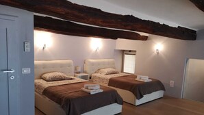 Un dormitorio con dos camas, vigas de madera y luces fijadas a la pared.