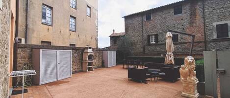 A courtyard with outdoor seating, a stone building, and a statue.