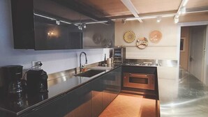 Una cocina moderna con armarios oscuros, una isla central y encimera de acero inoxidable.
