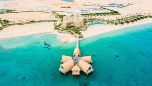 An aerial view of a resort with a central building surrounded by a beach and clear turquoise waters. - Tawila Island Resort (Hurghada)