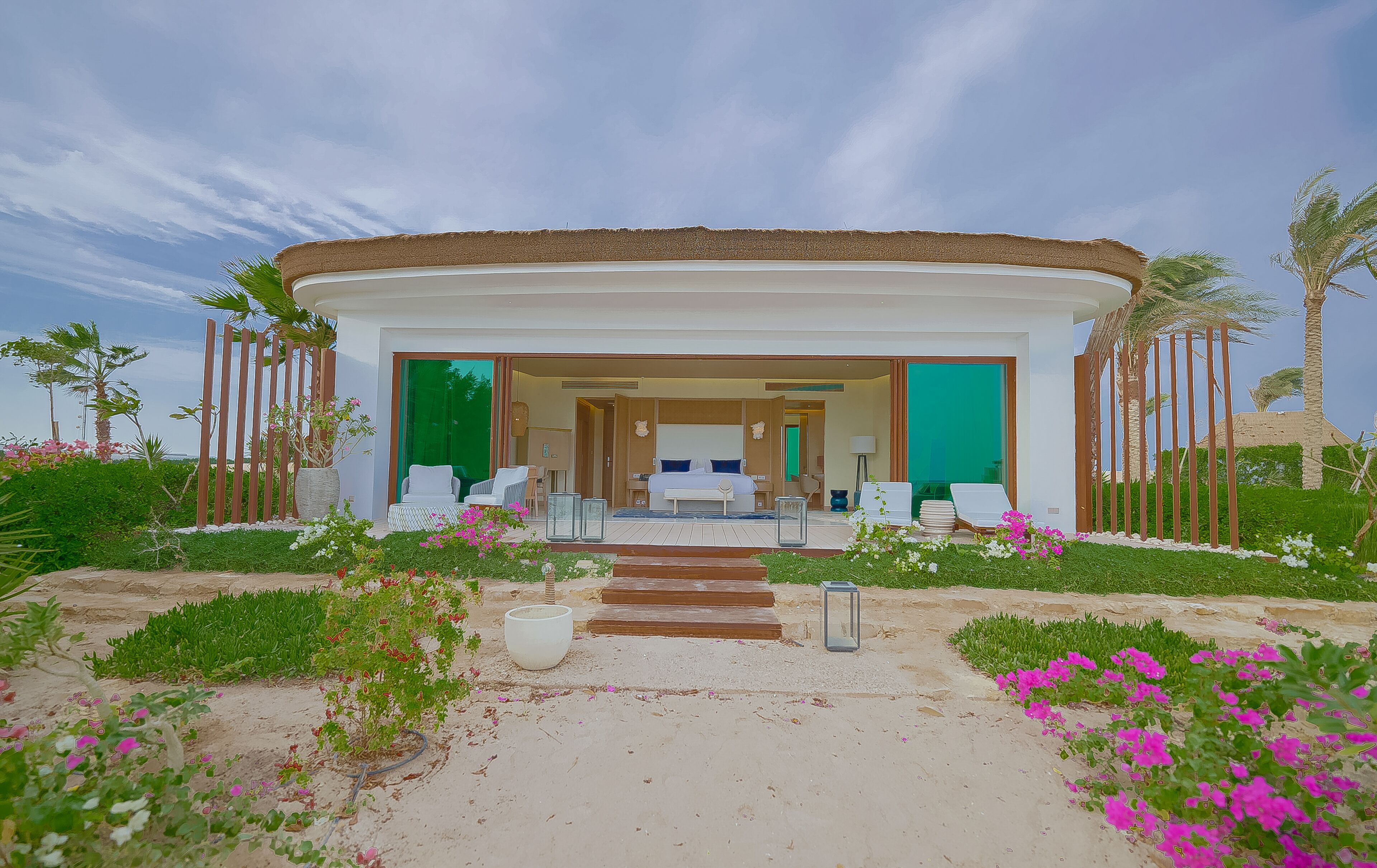 A modern resort with a circular structure, a central seating area, and a visible bedroom with a large bed.