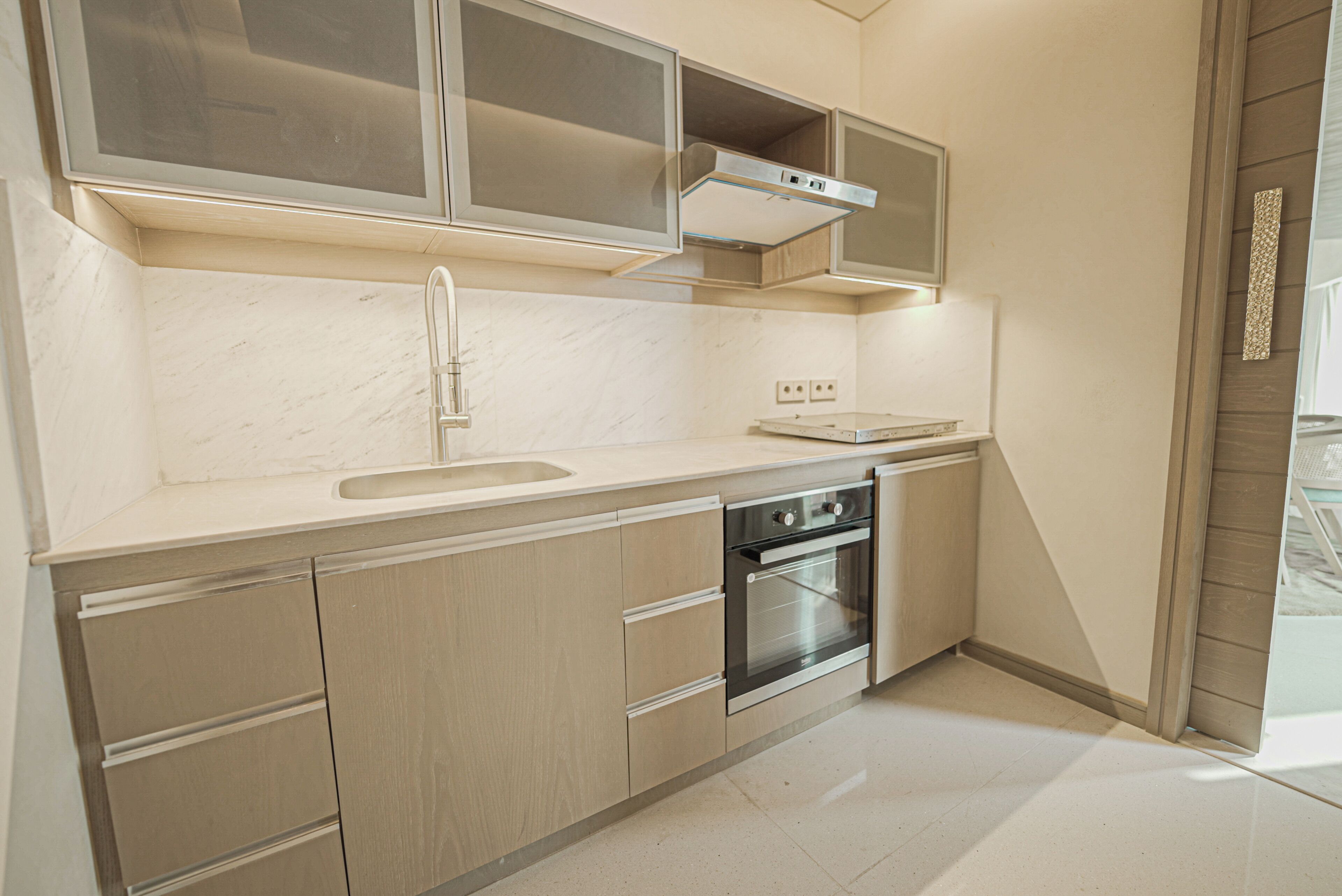 Een moderne keuken met een roestvrijstalen oven, een dubbele spoelbak en kastjes van licht hout.