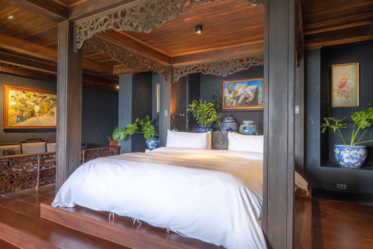 A bedroom with a large bed, wooden ceiling, and decorative wall panels.