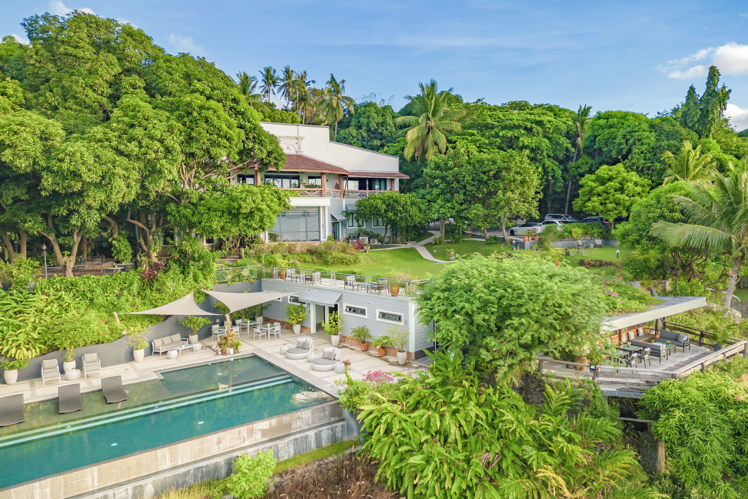 A modern resort with a swimming pool, outdoor seating, and lush greenery.