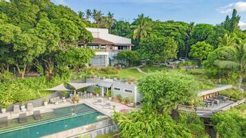A modern resort with a swimming pool, outdoor seating, and lush greenery.