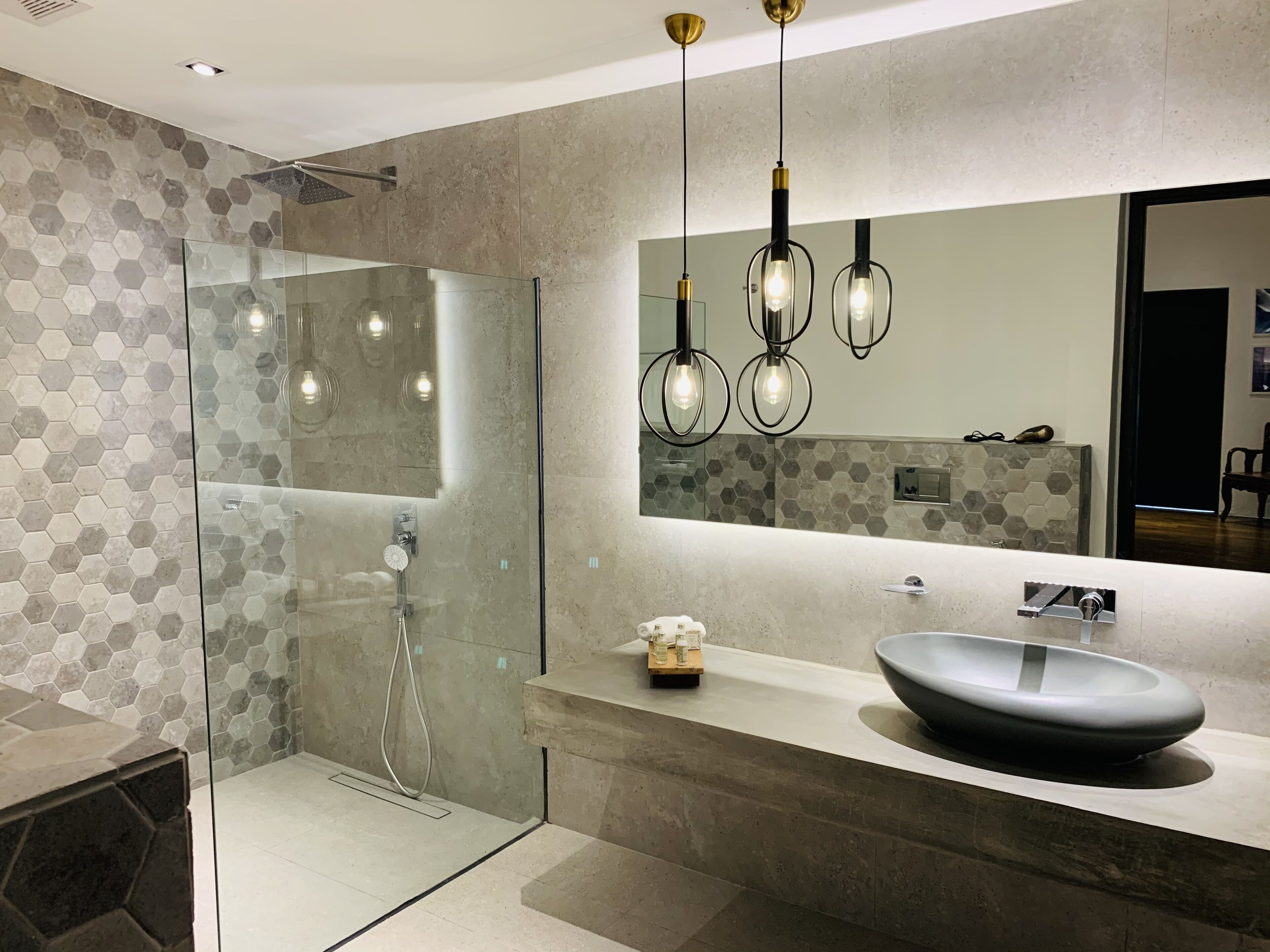 A modern bathroom with a glass shower enclosure, a large mirror, and a vessel sink.