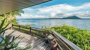 Une terrasse en bois dotée d’une balustrade, d’où l’on peut admirer un plan d’eau, avec une montagne en arrière-plan.