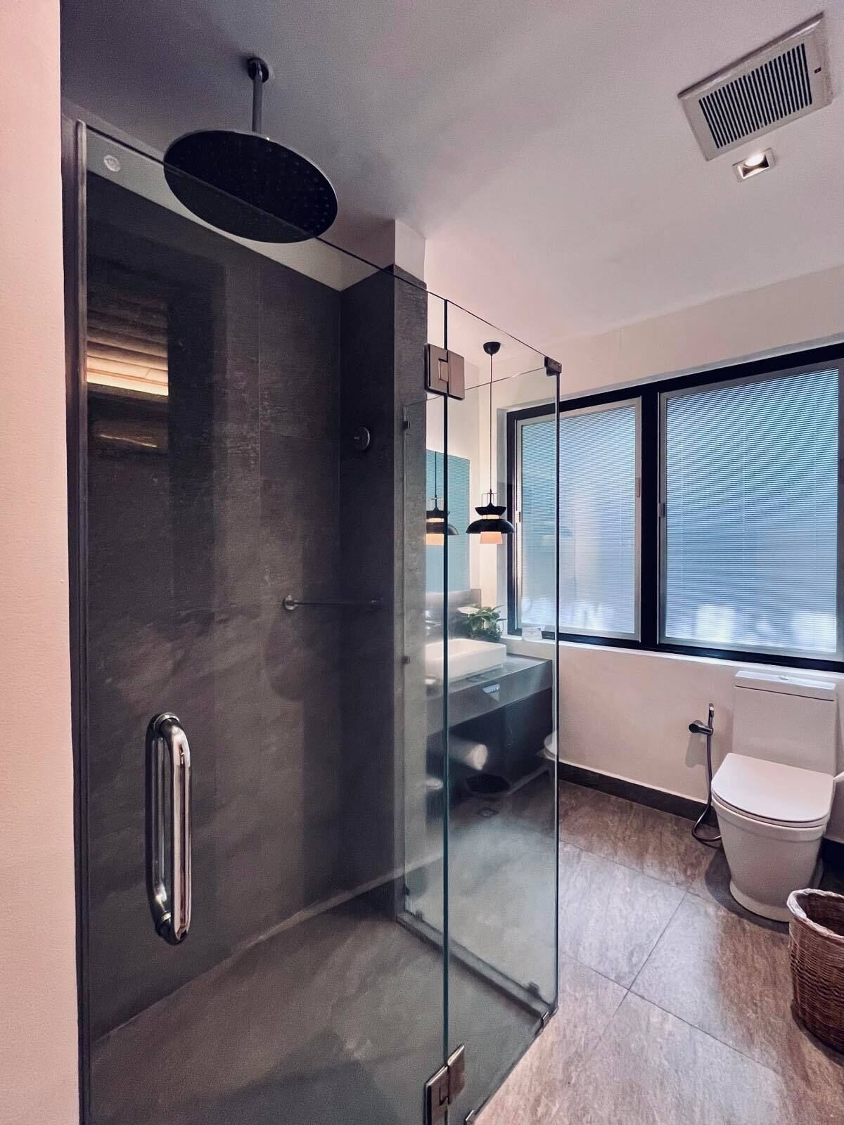 A modern bathroom with a glass-enclosed shower, a toilet, and a sink.