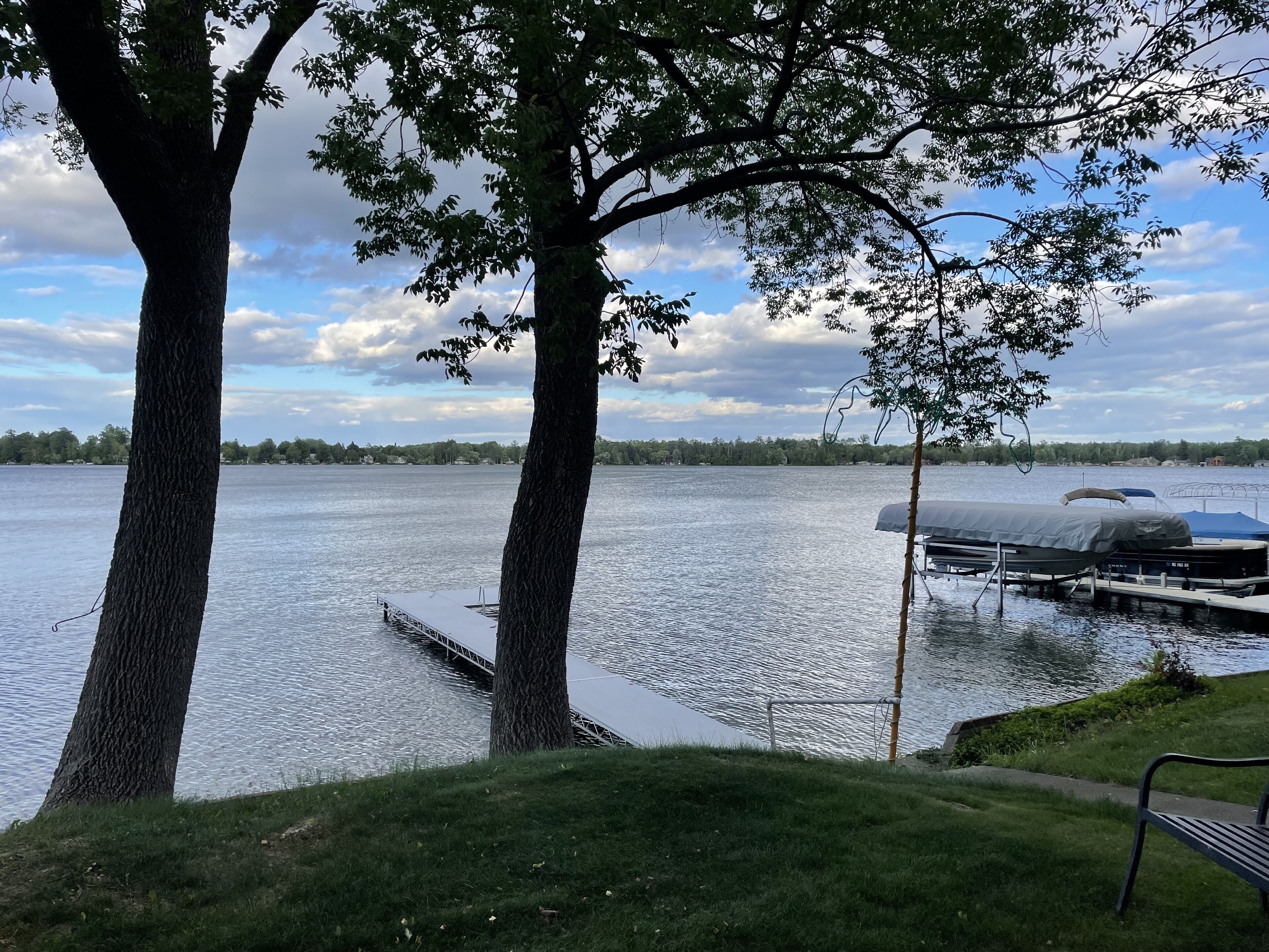 A lakeside view with docked boats and a grassy area.