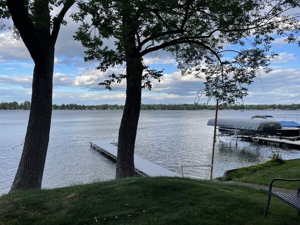 A lakeside view with docked boats and a grassy area.