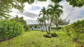 A lush garden with palm trees, a white building, and a bench. - Spacious + Serene Miami Home: Walk to Metrorail! (Miami)