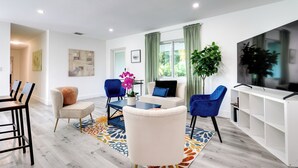 A modern living room with a sofa, chairs, a coffee table, and a TV. - Spacious + Serene Miami Home: Walk to Metrorail! (Miami)