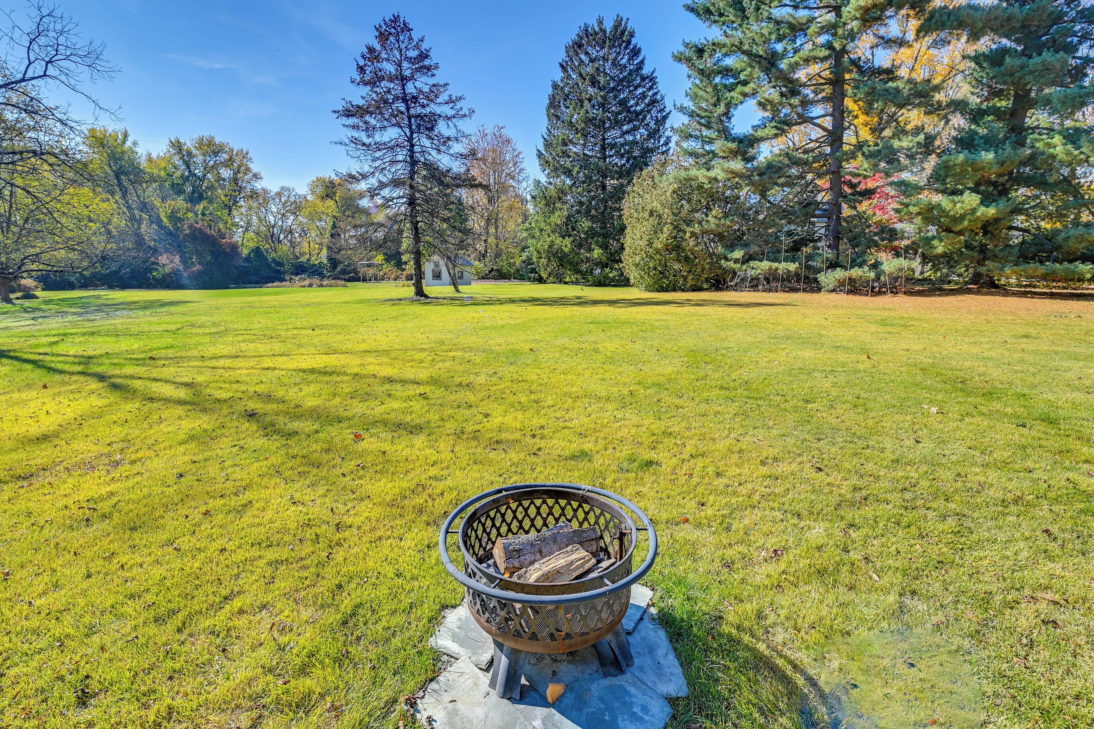 A grassy outdoor area with a metal fire pit in the foreground.