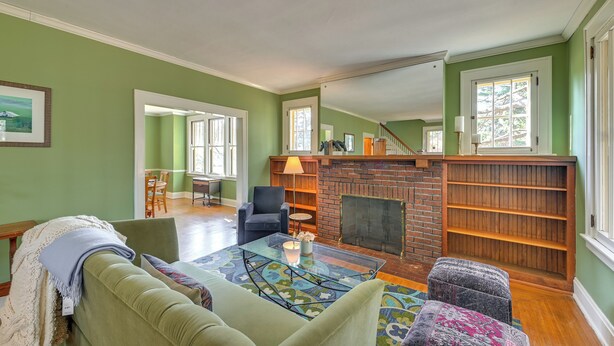 Una sala de estar con una pared verde, una chimenea, un sofá, una mesa de centro y una estantería.