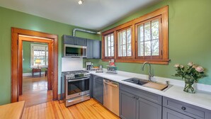 Una cocina con paredes verdes, armarios de madera, una estufa de acero inoxidable y un lavamanos.