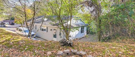 A house with a small porch, surrounded by trees and a leaf-covered ground.