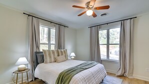 A bedroom with a bed, two bedside lamps, a ceiling fan, and large windows with curtains. - Centrally Located Home ~ Steps to Oxford Square! (Oxford)