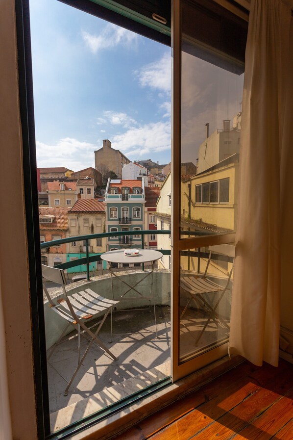 A balcony with a table and chairs, overlooking a cityscape with colorful buildings.