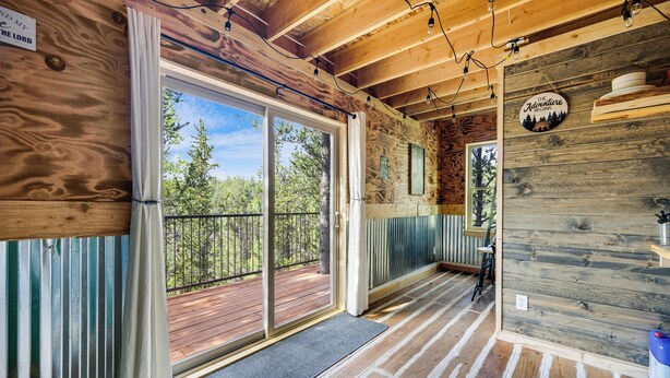 L’intérieur d’un chalet en bois, doté d’une terrasse, de grandes fenêtres et d’une enseigne indiquant : « The Adventure Lodge ».