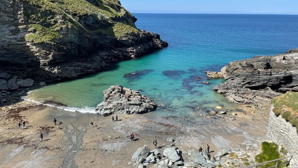 A coastal landscape with rocky terrain and clear blue waters.